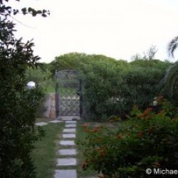 Blick auf das Gartentor und das umzäunte Grundstück der Ferienvilla Ginster an der Costa Rei, Sardinien