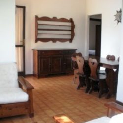 Blick ins Wohhnzimmer mit Anrichte, Esstisch und Sitzgruppe der Ferienwohnungen Ginster an der Costa Rei, Sardinien