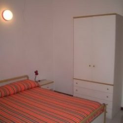 Schlafzimmer mit Doppelbett und Kleiderschrank der Ferienwohnung Mimose an der Costa Rei, Sardinien