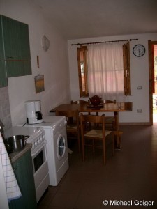 Küchenzeile mit Esstisch und Waschmaschine in den Ferienhäusern Ginestre an der Costa Rei, Sardinien