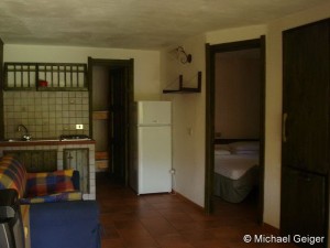 Wohnzimmer mit Couch und Küchenzeile des Ferienhauses India an der Costa Rei, Sardinien