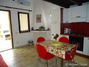Wohn- und Essbereich mit Küchenzeile und offenem Kamin in den Ferienhäusern Turagri an der Costa Rei, Sardinien