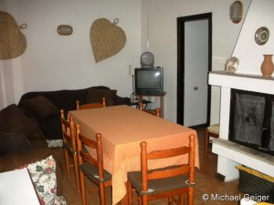 Wohnzimmer mit Kamin, Esstisch und Sitzgruppe in der Ferienvilla Ginster an der Costa Rei, Sardinien