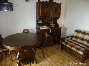 Wohnzimmerm mit Anrichte, Sitzgruppe und Sessel in der Ferienwohnung Ginestre Basse an der Costa Rei, Sardinien