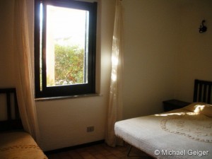 Schlafzimmer mit drei Betten in der Ferienwohnung Ginster an der Costa Rei, Sardinien