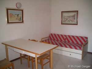 Wohnzimmer mit Auziehcouch und Esstisch der Ferienwohnung Mimose an der Costa Rei, Sardinien